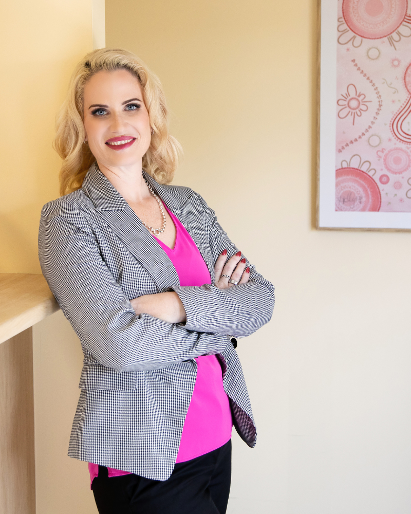 Vanessa Norman standing with her arms crossed, wearing a pink top and grey blazer